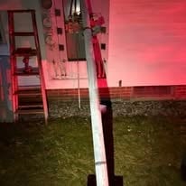 Pink shipping container or mobile structure at dusk with a white line on grass, illuminated by red-pink lighting
