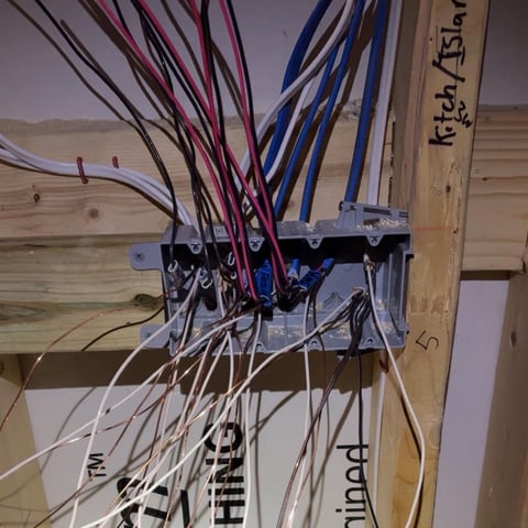 Electrical junction box with multiple colored wires (black, red, blue, white) connected to terminal block on wooden mount